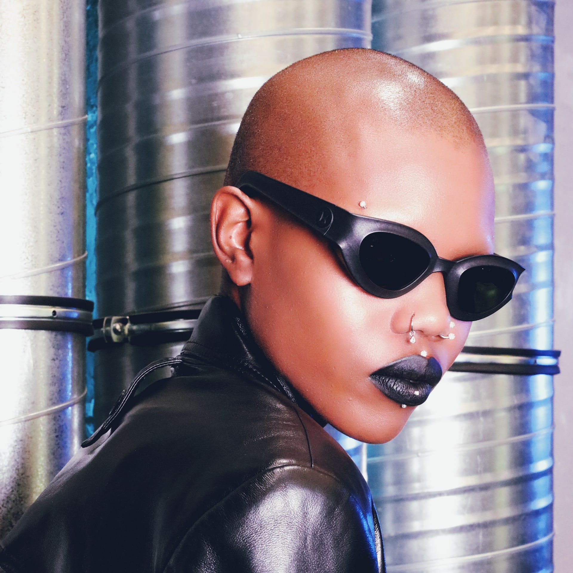 Portrait of model wearing REFRAMD Afronaut 3D-printed parametric sunglasses in industrial studio setting